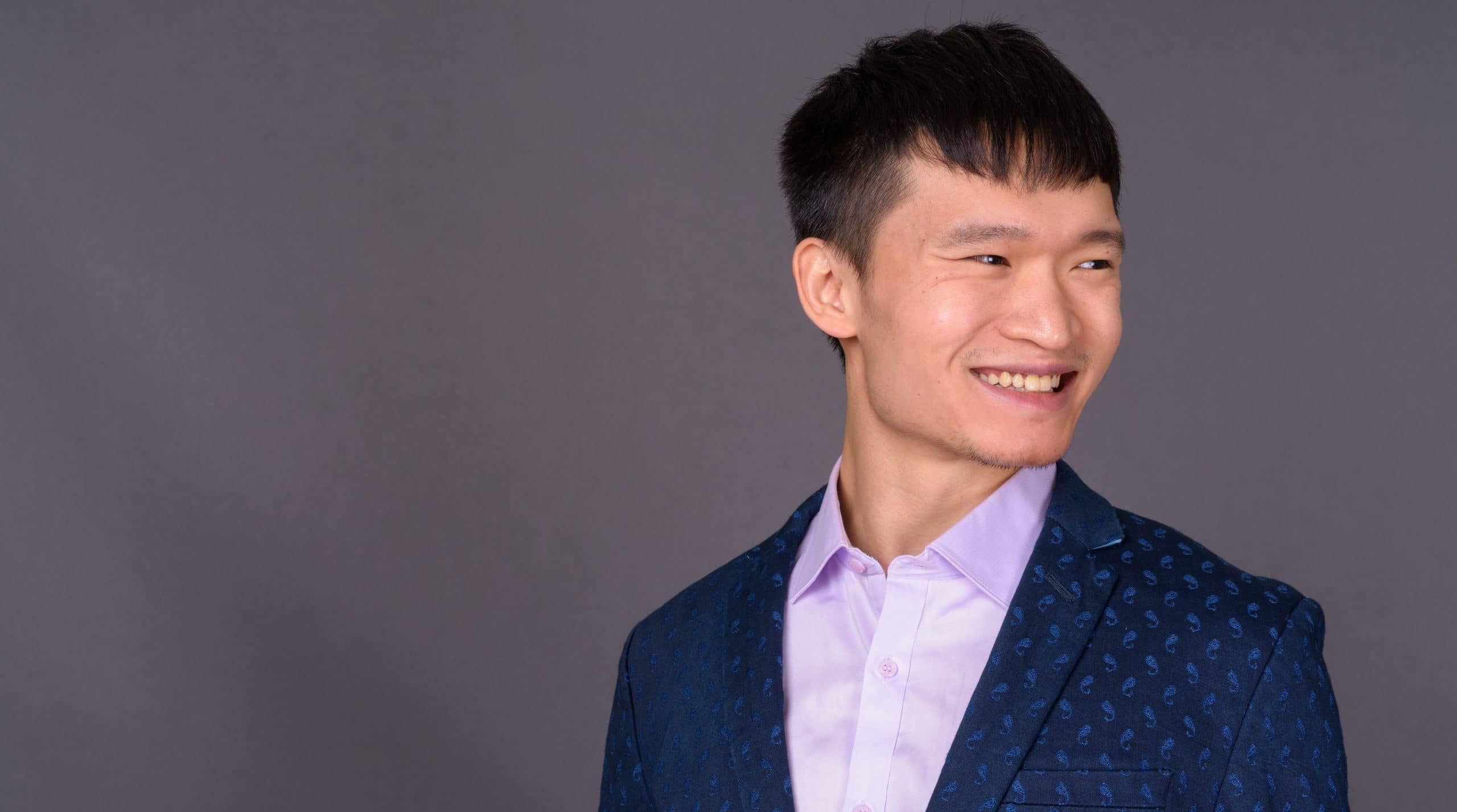 Portrait of young Chinese businessman against gray background