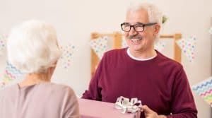 Happy retired man taking giftbox with present given by his wife