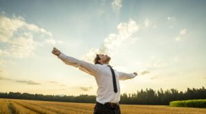 thankful-businessman-with-open-arms-at-the-field-PEBDRQD-1-scaled-e1618392382948